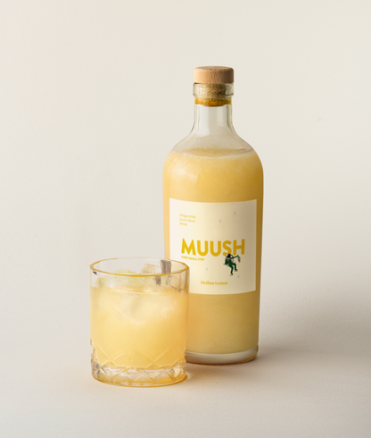 Bottle and glass of MUUSH SICILIAN LEMON ELIXIR drink on a light background