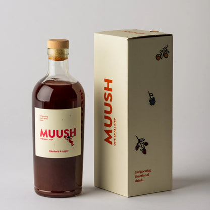 Bottle and box of Muush Rhubarb and apple on a gray background